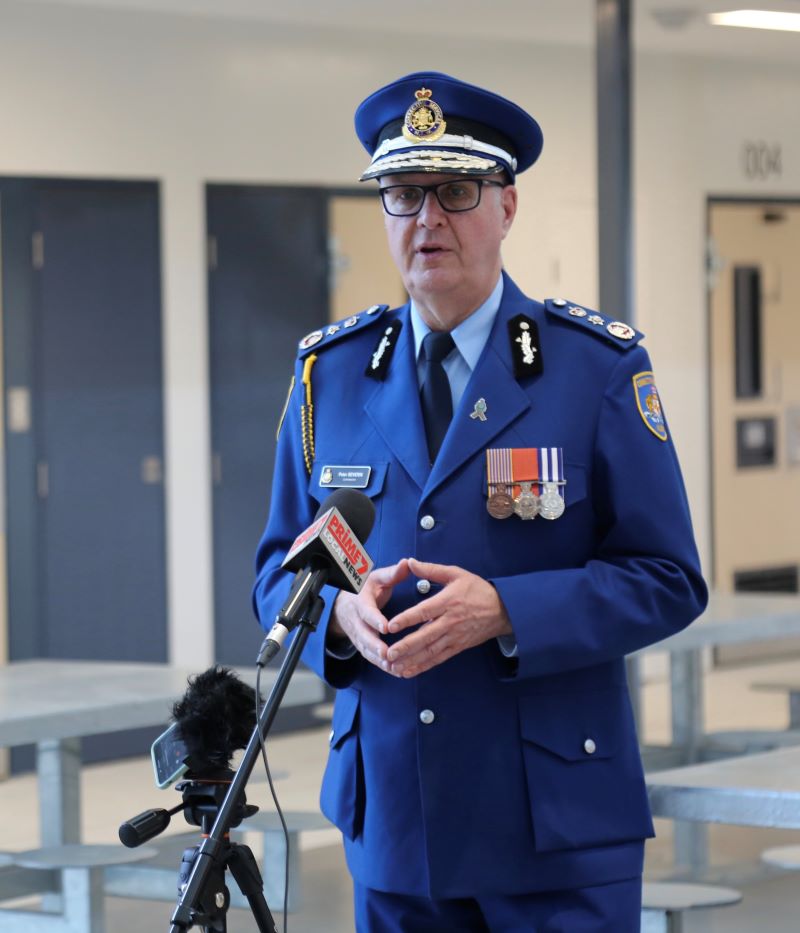 Man standing in navy suit uniform, in front of microphone