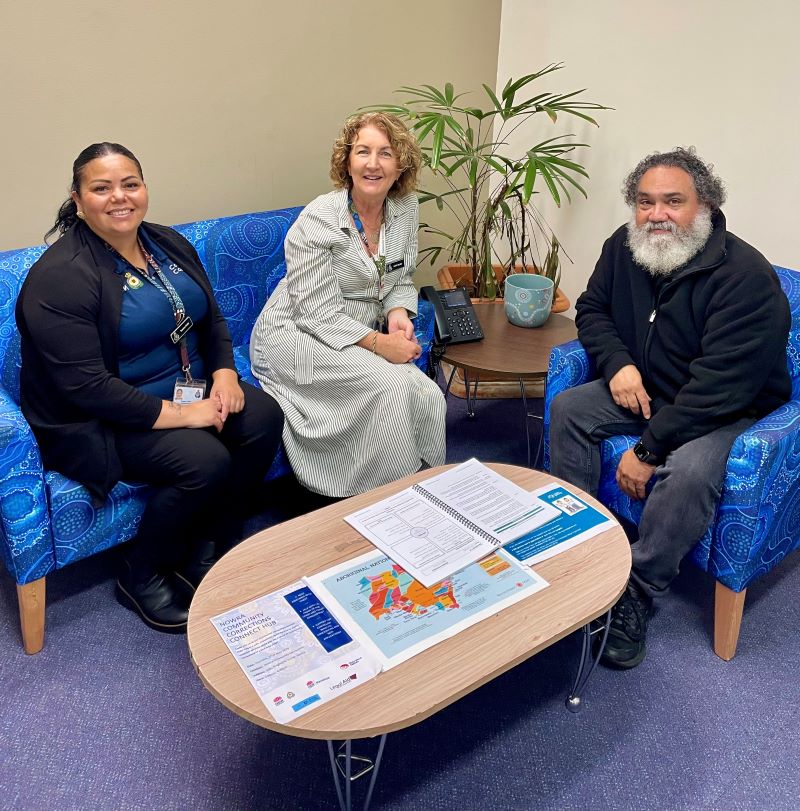 Three people seated on couches around a coffee table 