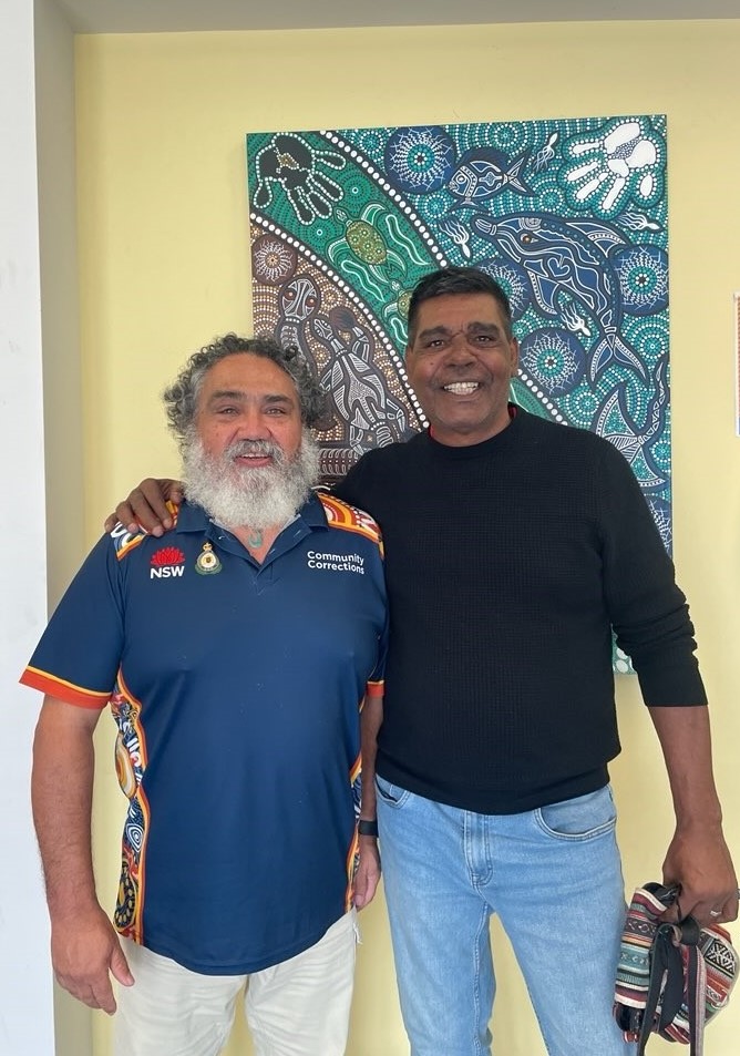 Two men standing with arms around each other's shoulders