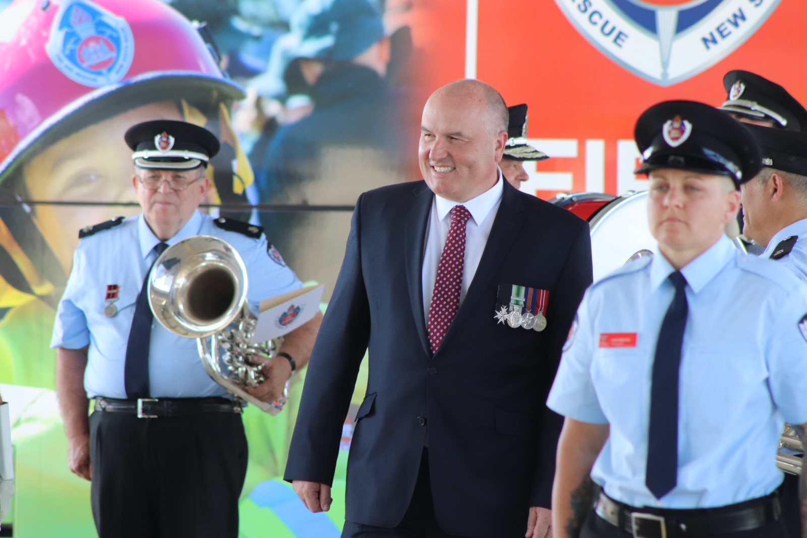 This is an image of Minister for Police and Emergency Services David Elliott congratulating the 16 new firefighters.